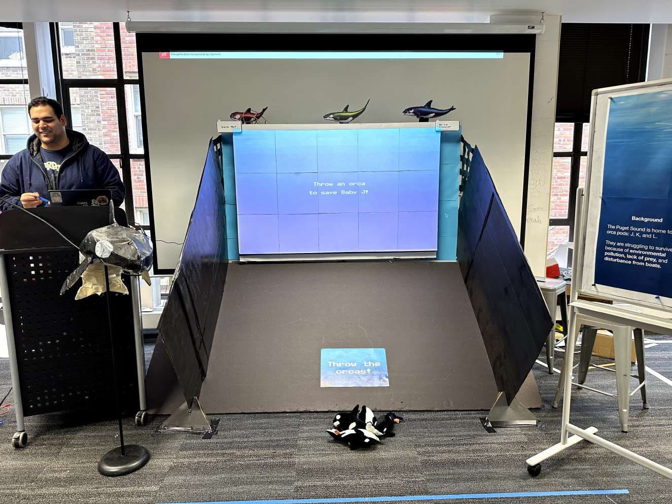 Booth with Throw the orcas sign and plushies at the return slide