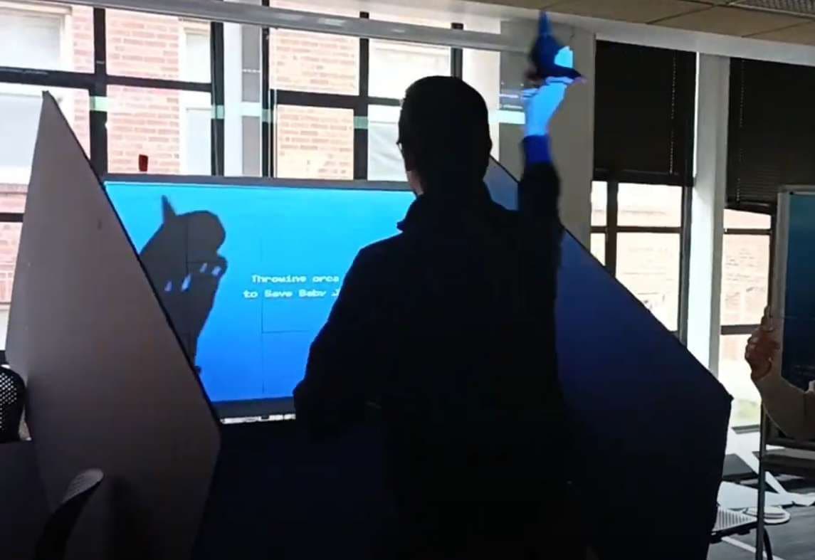 Person holding an orca plushie up toward the game screen